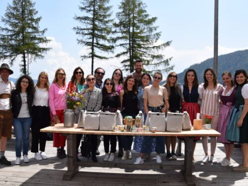 Un gruppo di persone posa in posa dietro un tavolo di legno su una terrazza panoramica in Val Sarentino.