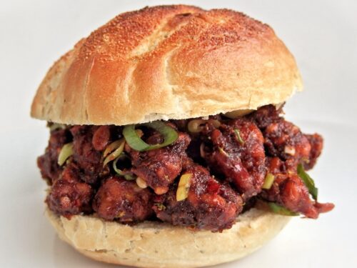 Un panino farcito con cubetti di tempeh marinati in una salsa scura e guarniti con rondelle di cipollotto fresco.