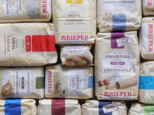 Una selezione di vari pacchetti di farina e semola del marchio Rieper disposti in una composizione compatta.