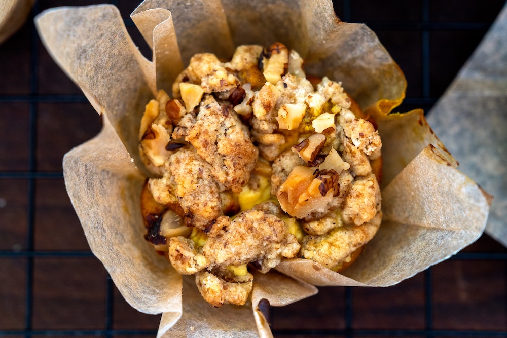 Muffin cotto in pirottino di carta con una croccante copertura di crumble e noci in vista dall'alto.